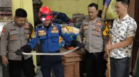 Petugas Polsek Sukodadi dan Damkar Lamongan mengevakuasi ular masuk ke rumah warga .