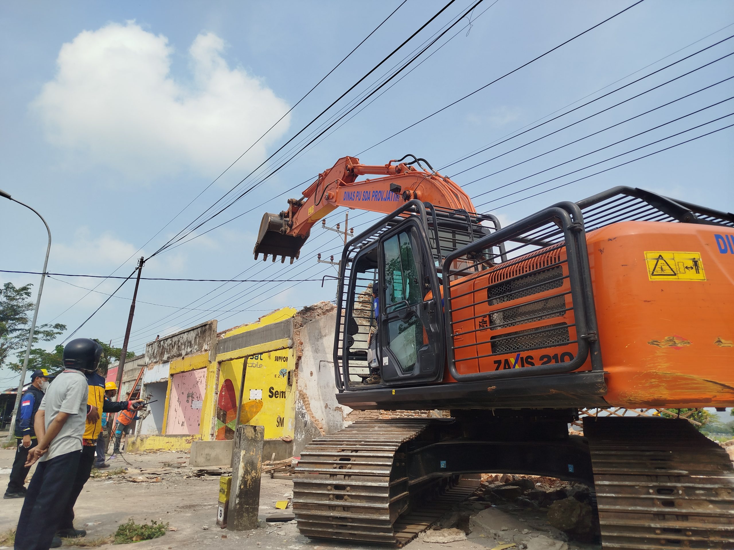 Petugas saat menurunkan alat berat untuk membongkar bangunan permanen.