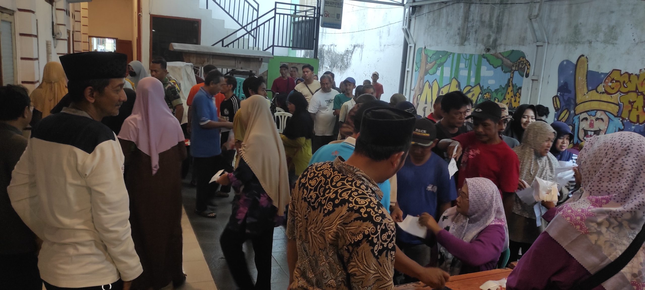 Ratusan warga Kepatihan saat mengantri mendapatkan bantuan di halaman balai desa.
