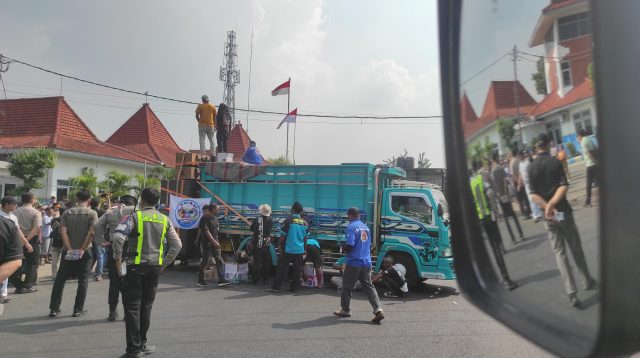 Sebanyak puluhan armada truk tergabung di Gerakan Sopir Jawa Timur (GSJT) gelar aksi demo dan tutup ruas depan kantor Dishub Jombang di Jalan Mastrip Desa Kepuhkembeng, Kecamatan Peterongan, Kabupaten Jombang.