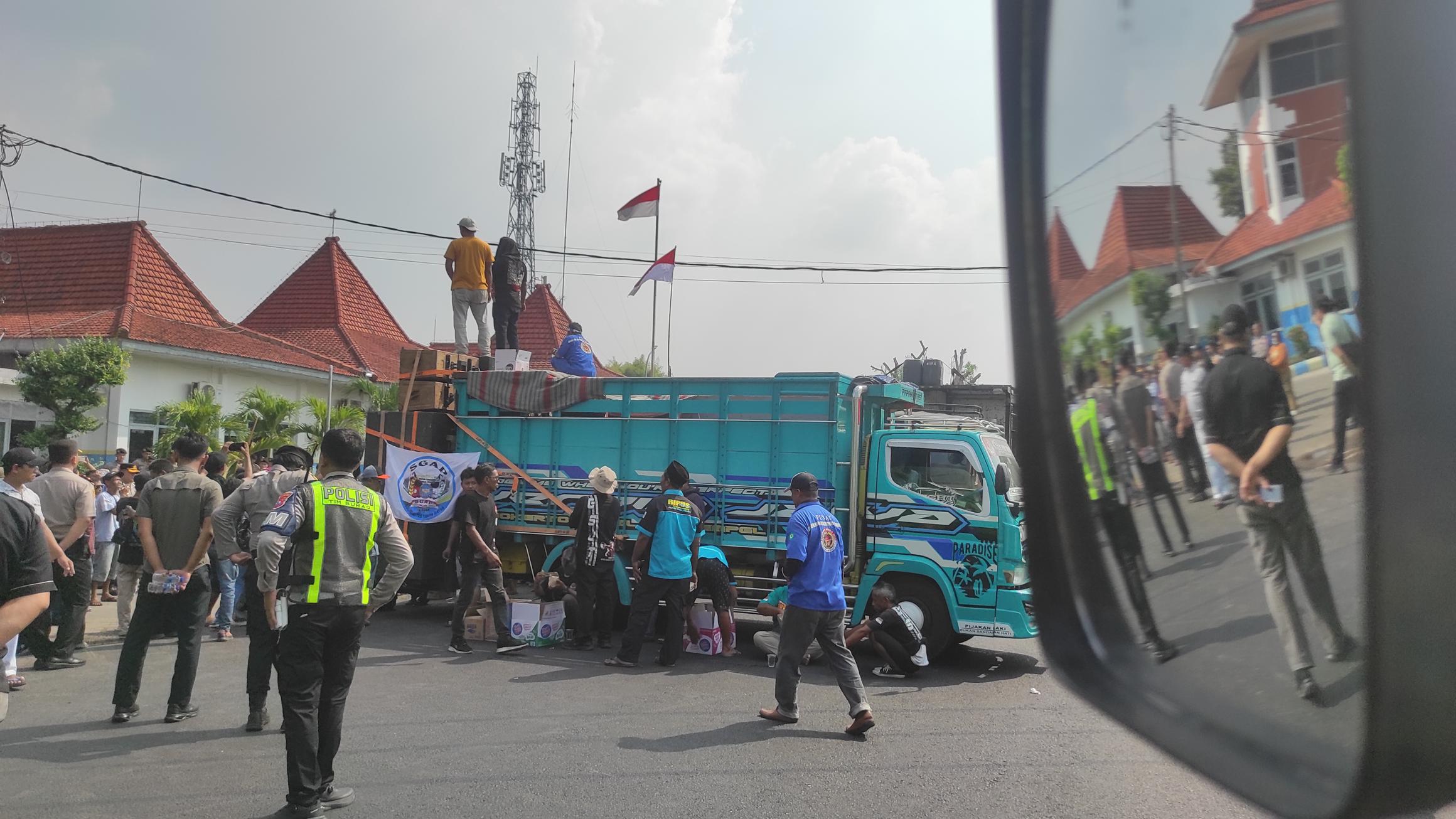 Sebanyak puluhan armada truk tergabung di Gerakan Sopir Jawa Timur (GSJT) gelar aksi demo dan tutup ruas depan kantor Dishub Jombang di Jalan Mastrip Desa Kepuhkembeng, Kecamatan Peterongan, Kabupaten Jombang.