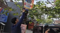 Reklame Petugas Satpol PP Tulungagung saat melakukan penertiban papan reklame yang dipasang di pohon.