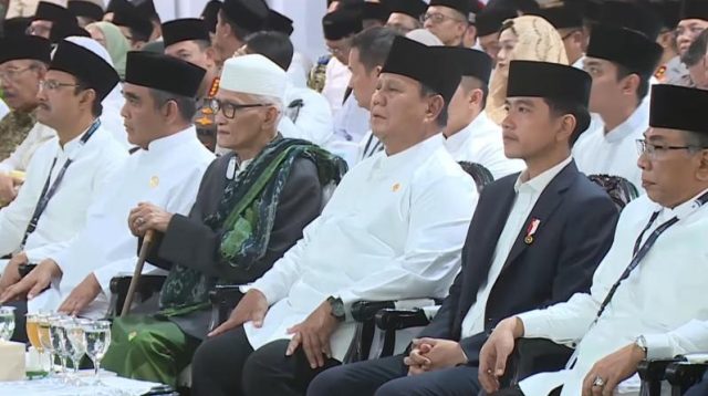 Presiden Republik Indonesia, Prabowo Subianto (tengah, mengenakan baju koko putih dan peci hitam), Wakil Presiden RI, Gibran Rakabuming Raka (kanan Prabowo, mengenakan setelan jas hitam, kemeja putih, dan peci hitam), Rais 'Aam Pengurus Besar Nahdlatul Ulama (PBNU), KH Miftachul Akhyar (kiri Prabowo, mengenakan peci putih/kopiah haji dan berselendang hijau) dan beberapa ulama lainnya.