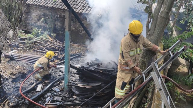 Petugas Damkar Ngadiluwih padamkan api yang membakar tumpukan kayu di Kraton Mojo Senin siang.