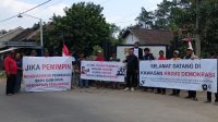 Warga bersama sejumlah Ketua RT membentangkan spanduk berisi kritik terhadap kebijakan pemerintah desa di perempatan Desa Duwet, Kecamatan Wates, Kabupaten Kediri.