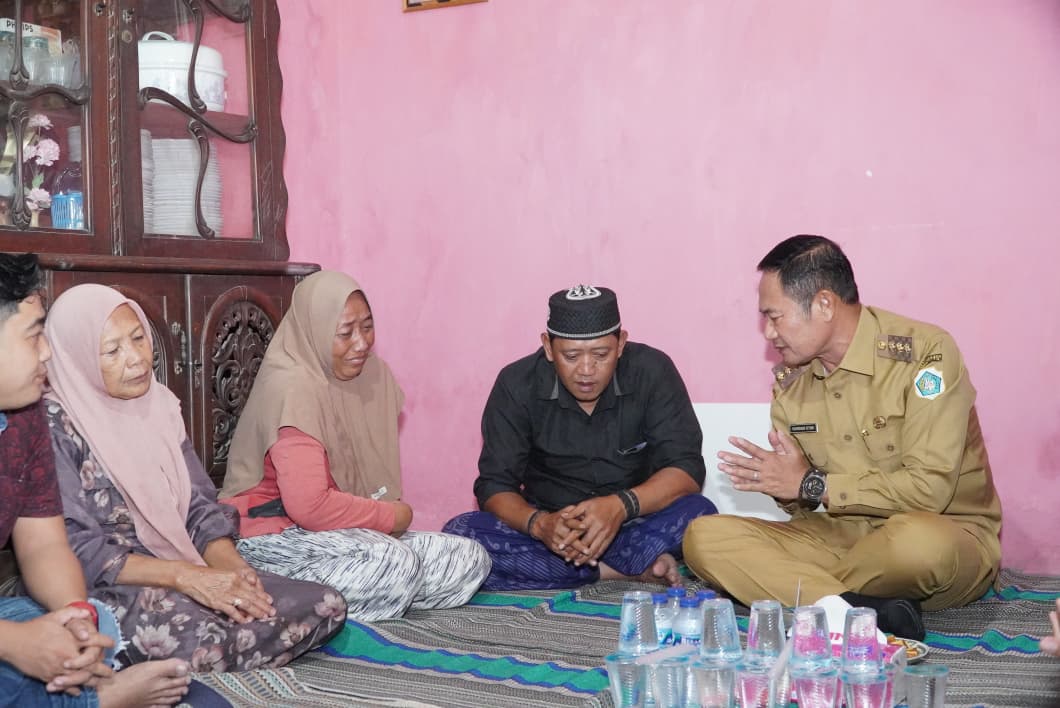 Bupati Lamongan Yuhronur Efendi menyerahkan santunan jaminan kecelakaan kerja kepada keluarga korban.