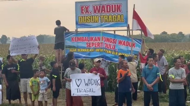 Warga membentangkan spanduk penolakan klaim kepemilikan tanah eks waduk di Dusun Tragal, Desa Kedungpapar, Sumobito, Jombang.